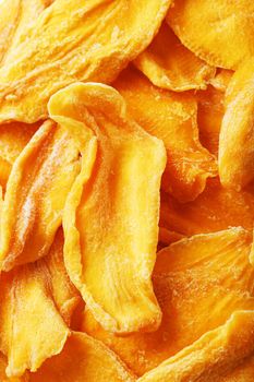 Dried sweet mango fruit slices as textural orange background in full screen