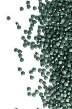 Green tablets made of natural organic spirulina on a white background with free space