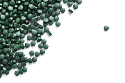 Vegetarian vitamins from Spirulina are scattered on a white background with free space