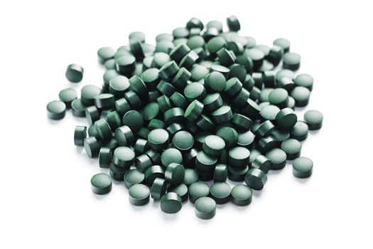 Green tablets made of natural organic spirulina on a white background with free space