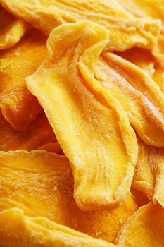 Dried sweet mango fruit slices as textural orange background in full screen