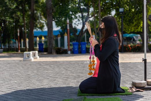 Thai buddhism people in buddhist pray for benefaction worship by incense and garland to Buddha or spirit-house at shrine or Thai temple (Wat Thai)