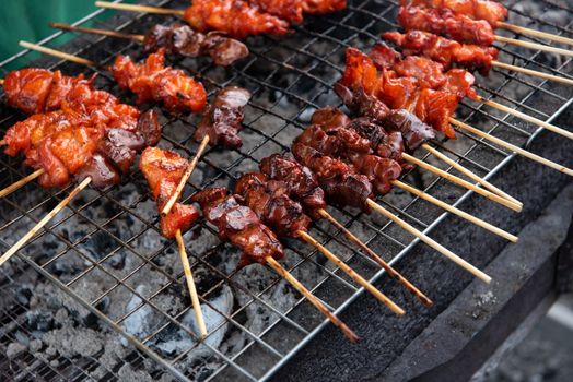 Grilled chicken sauce is a Thai barbeque food by chicken and sauce cooking on charcoal with flames at Thai street food market