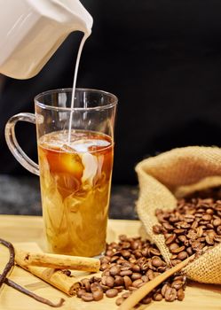 Shot of coffee beans and a cup of cinnamon and vanilla coffee.