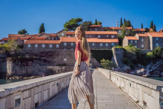 Woman tourist on background of beautiful view of the island of St. Stephen, Sveti Stefan on the Budva Riviera, Budva, Montenegro. Travel to Montenegro concept.