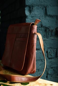 close-up photo of orange leather messanger bag on a wooden table. indoor photo