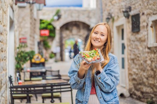 Young woman tourist eating traditional pizza in the old town of Budva. Travel to Montenegro concept.