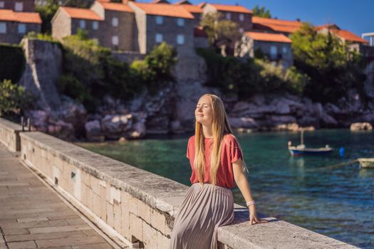 Woman tourist on background of beautiful view of the island of St. Stephen, Sveti Stefan on the Budva Riviera, Budva, Montenegro. Travel to Montenegro concept.