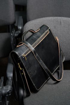 Black leather briefcase with antique and retro look for man on a office chair.