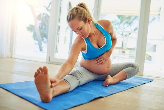 Shot of a pregnant woman working out on an exercise mat at home.