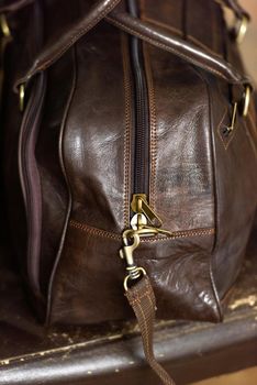 Leather brown travel bag, on a brown leather chair. Indoor photo. soft light