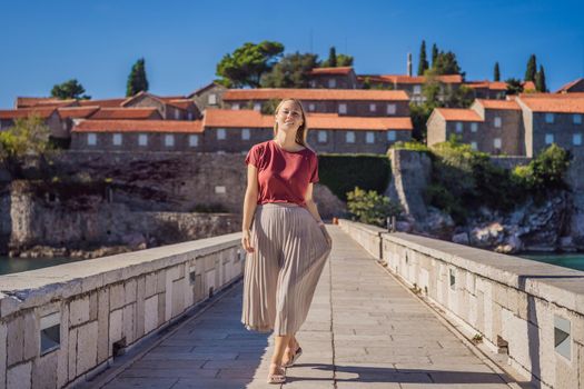 Woman tourist on background of beautiful view of the island of St. Stephen, Sveti Stefan on the Budva Riviera, Budva, Montenegro. Travel to Montenegro concept.