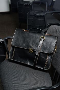 Black leather briefcase with antique and retro look for man on a office chair.