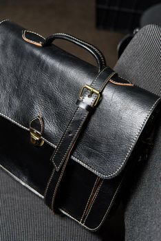 Black leather briefcase with antique and retro look for man on a office chair.