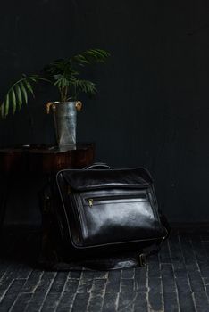 Leather black travel bag, on a black wooden floor. soft light