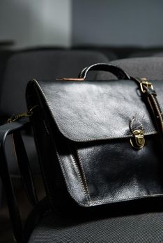 Black leather briefcase with antique and retro look for man on a office chair.