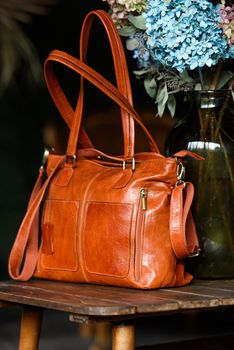 close-up photo of orange leather bag on a wooden table. indoor photo