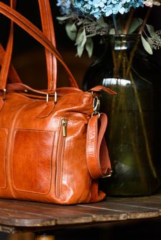 close-up photo of orange leather bag on a wooden table. indoor photo