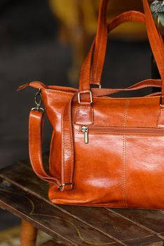 close-up photo of orange leather bag on a wooden table. indoor photo