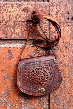 small brown women's leather bag with a carved pattern. Outdoors photo