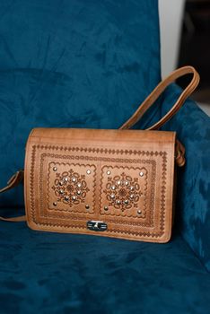 small brown women's leather bag with a carved pattern. indoor photo