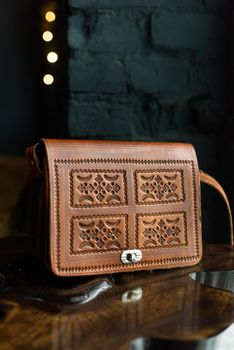 small brown women's leather bag with a carved pattern. indoor photo