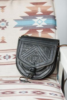 small brown women's leather bag with a carved pattern. indoor photo