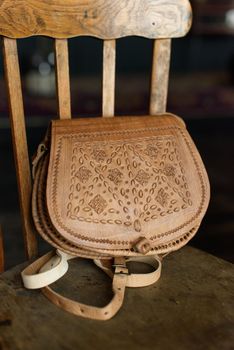 small brown women's leather bag with a carved pattern. indoor photo