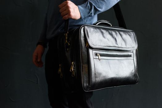 Man holding black leather travel bag. Soft light. Indoor photo