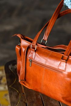 close-up photo of orange leather bag on a wooden table. indoor photo