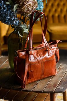 close-up photo of orange leather bag on a wooden table. indoor photo