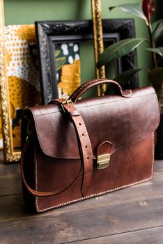 brown leather briefcase with antique and retro look for man on a wooden floor. Indoor photo.