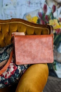 close-up photo of orange leather bag on a vintage sofa. indoor photo