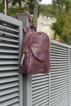 burgundy leather backpack on the metal fence.