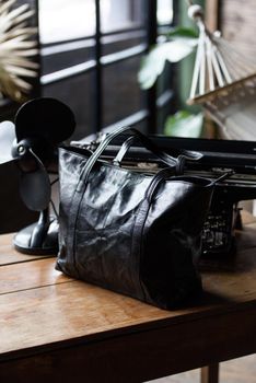 close-up photo of black leather bag on a wooden table. indoor photo