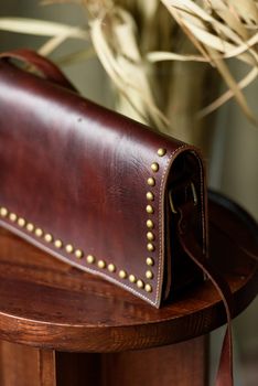 small brown women's leather bag with rivets selective focus. indoor photo