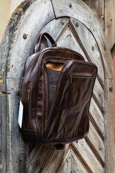 Brown leather backpack on the wooden door.