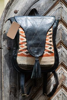 Black leather backpack with a pattern on the wooden door. Street photo