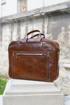 Brown men's shoulder leather bag for a documents and laptop. Outdoors.