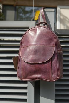 burgundy leather backpack on the metal fence.