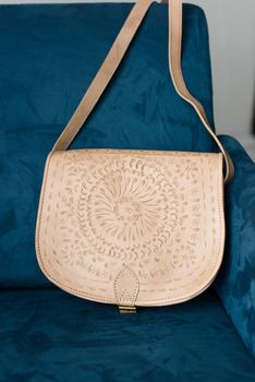 small brown women's leather bag with a carved pattern. indoor photo