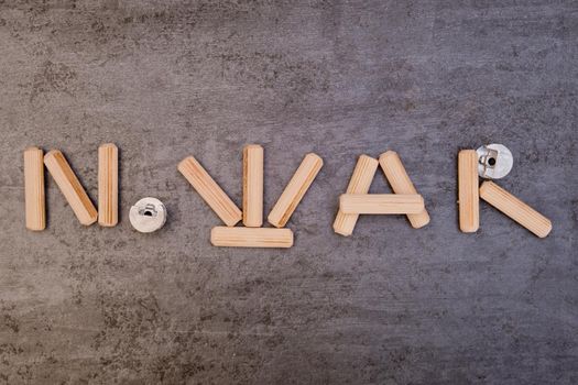 The phrase "No War" is written with wooden furniture pegs. Close-up.