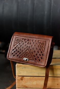 small brown women's leather bag with a carved pattern. indoor photo