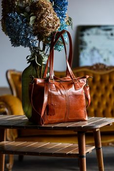 close-up photo of orange leather bag on a wooden table. indoor photo