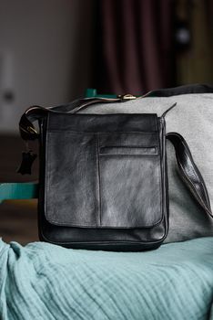 close-up photo of black messanger leather bag on a chair. indoor photo