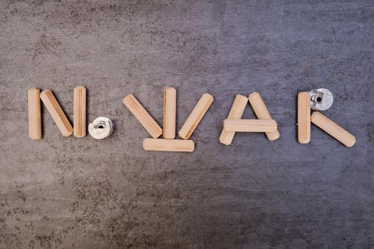 The phrase "No War" is written with wooden furniture pegs. Close-up.