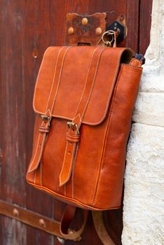 stylish leather backpack on a rustic wooden door.