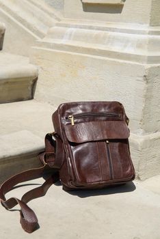 Outdoor photo of a brown leather Messenger bag. Close up.