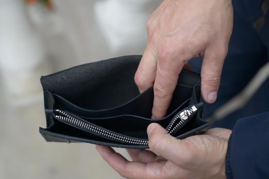 Man holding an empty black leather wallet. the concept of poverty and unemployment