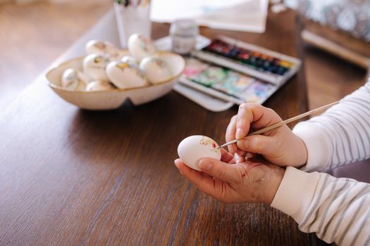 Woman painting a water colors on fantasy chicken eggs for Easter egg festival. Female drawing little yellow chick. The symbolic of Spring. Easter concept.